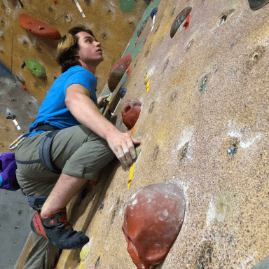 A male student tackles the climbing wall.