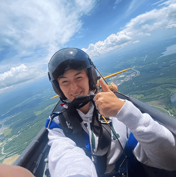 A student takes a selfie while flying high in the sky in a plane