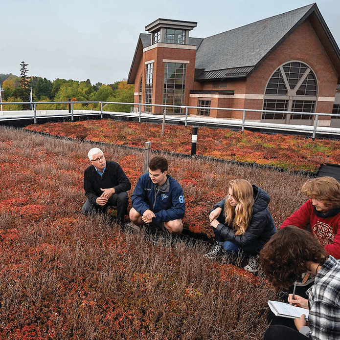 Professor talks to students on the plant-covered green roof of Aiken Hall