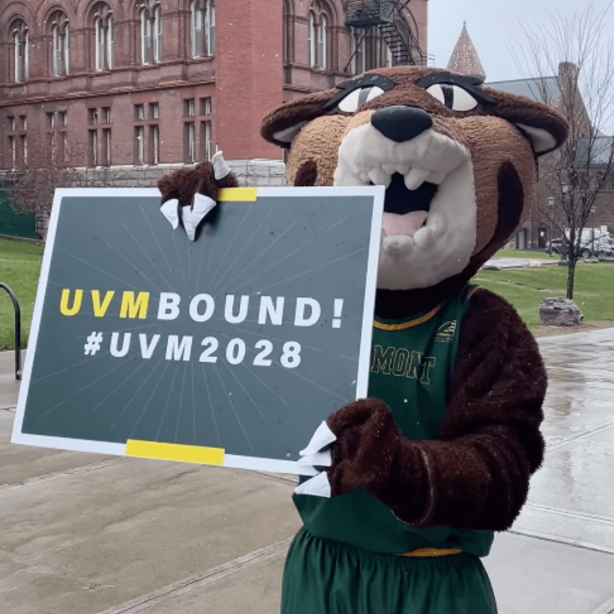 RallyCat holding a sign that reads "UVM Bound! #UVM2028"