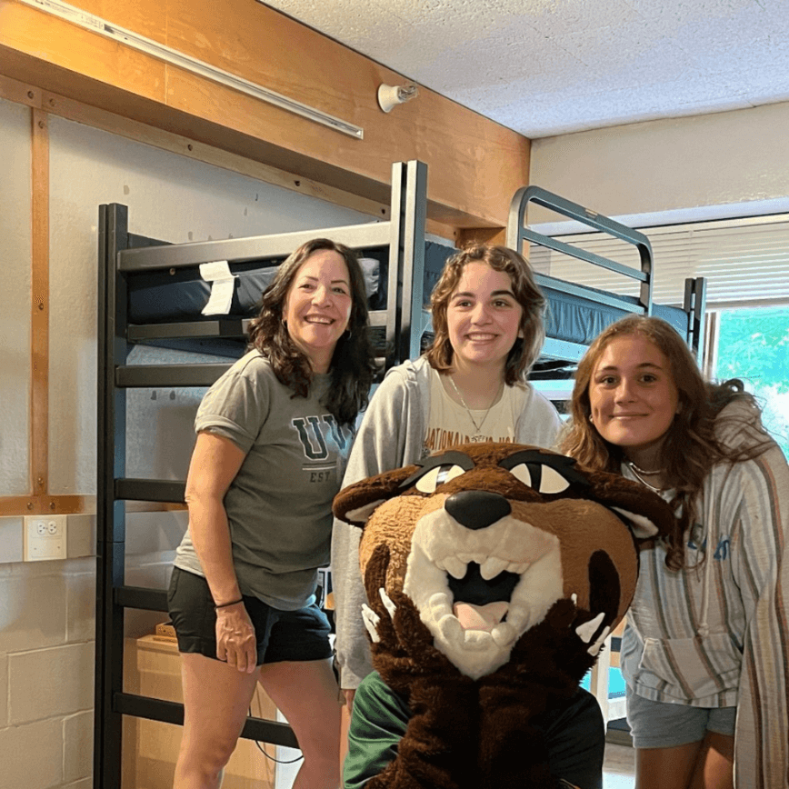 Three people pose with the Rally Cat mascot