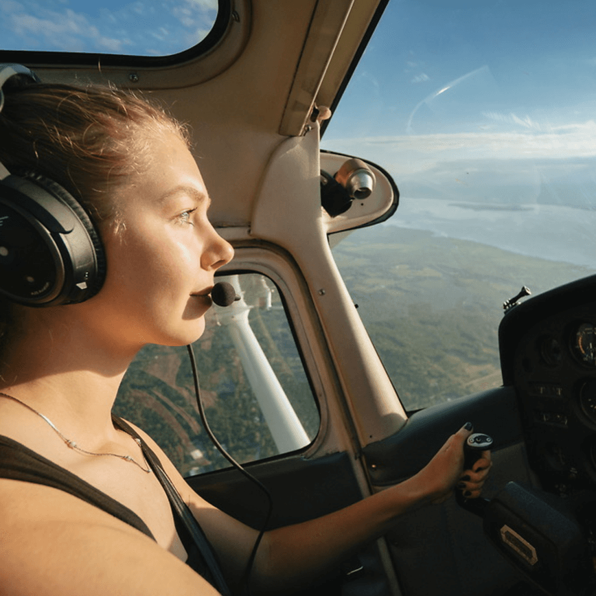 A female student in the cockpit of a plane flying above a lake.